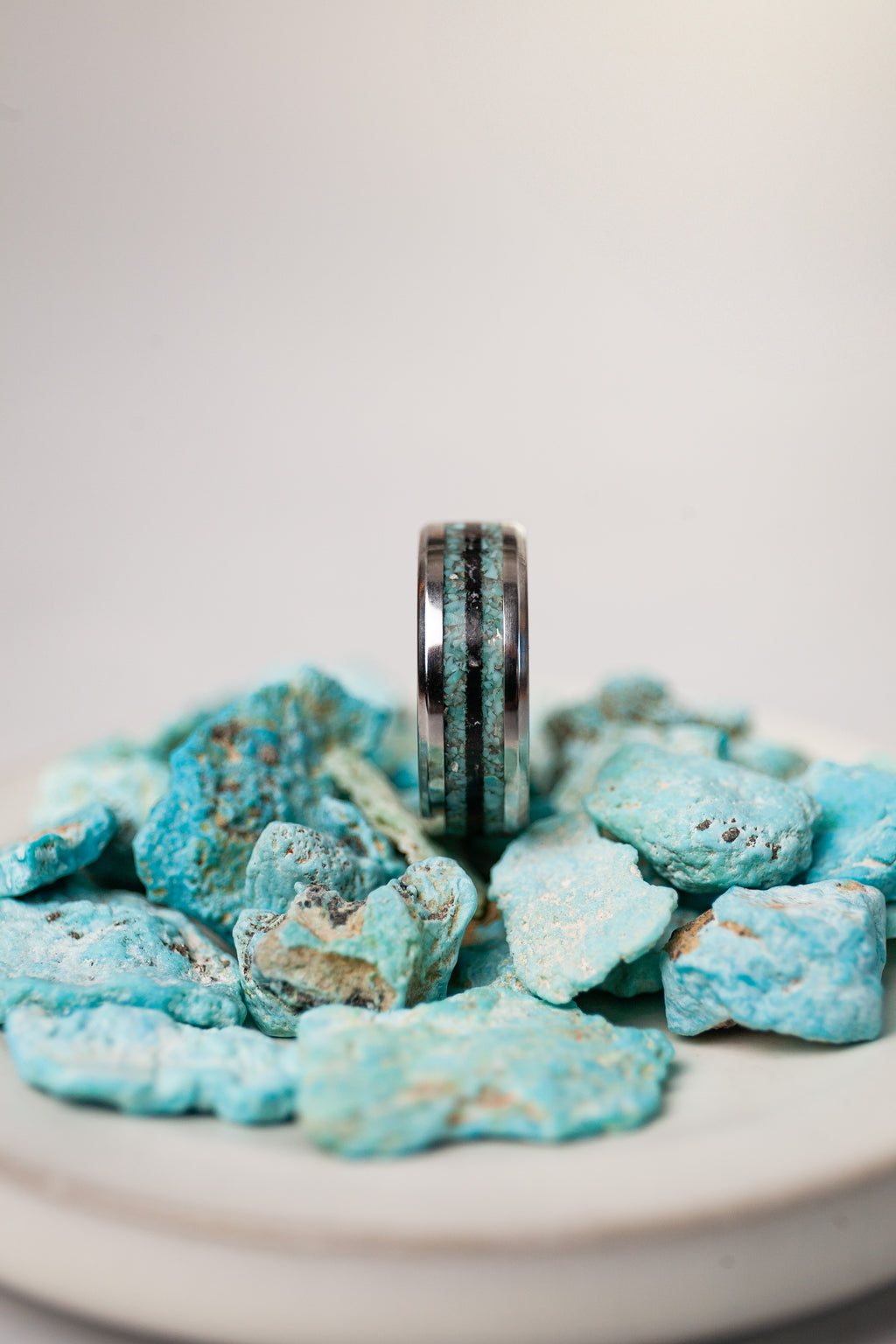 Silver ring on a pile of blue rocks with a white background