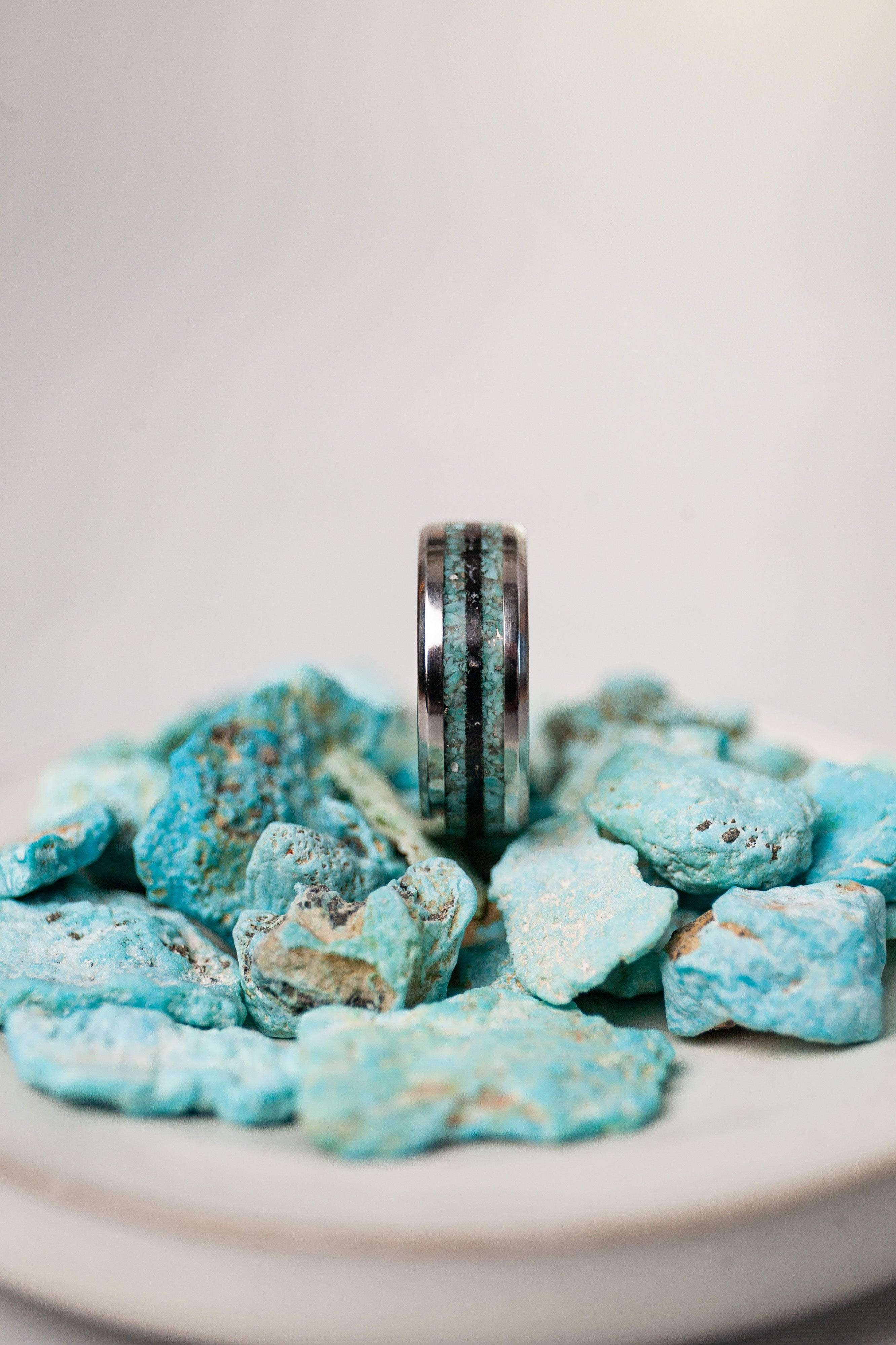 Silver ring on a pile of blue rocks with a white background